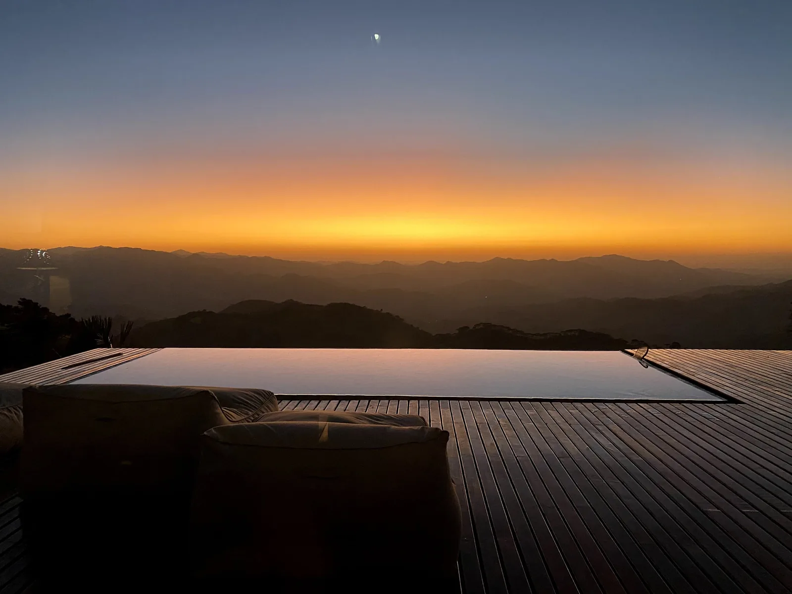 Anoitecer: a lua sobre as montanhas e o céu azul profundo refletidos na água